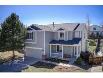 Charming two-story home featuring a cozy front porch, attached garage, and manicured lawn at 9855 Chatswood Trl, Highlands Ranch, CO 80126