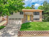 Charming split-level home with manicured lawn, brick accents, and a two-car garage at 1811 S Yank Ct, Lakewood, CO 80228