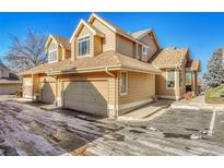 Tan two-story townhome with attached garage and snow-covered driveway at 2134 S Scranton Way, Aurora, CO 80014