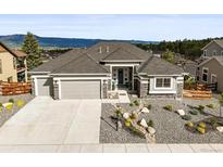 Beautiful home with a three-car garage, manicured rock garden, and attractive contrasting stone and siding accents at 16312 Morning Rise Ln, Monument, CO 80132