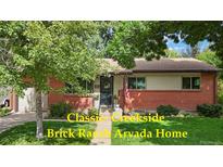 Charming brick ranch home with a manicured lawn, inviting front entrance, and an attached garage at 6371 Brooks Dr, Arvada, CO 80004