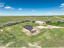 Expansive aerial view of a tan home and large shop, surrounded by green fields under a blue sky at 68251 E 96Th Ave, Byers, CO 80103