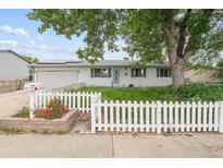 Charming single-story home with a white picket fence and solar panels on the roof at 5935 Blanca Ct, Golden, CO 80403