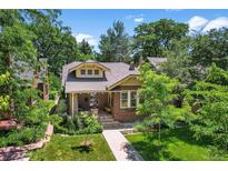 Charming brick home featuring a well-manicured lawn, mature trees, and inviting front porch at 836 Steele St, Denver, CO 80206