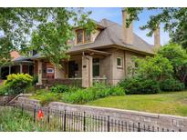 Charming brick home featuring a covered front porch, well-maintained landscaping, and mature trees at 2975 Irving St, Denver, CO 80211