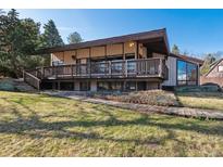 Two-story home with a large deck, lush lawn, and wooden pathway for relaxed outdoor enjoyment at 8 Morningside Dr, Wheat Ridge, CO 80215