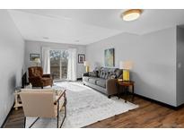 Bright living room with a gray sofa, wooden floors, and sliding glass doors to a balcony at 1606 Cottonwood Dr # 24S, Louisville, CO 80027