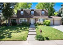 Charming two-story home with manicured lawn, lush landscaping, and a brick facade at 10366 E Ida Ave, Greenwood Village, CO 80111