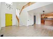 Bright, open-concept living space with high ceilings, wood floors and a modern chandelier at 465 Vernier Ct, Lafayette, CO 80026