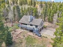 Charming home exterior featuring a wooded lot, deck, and a driveway leading to the garage at 10469 Christopher Dr, Conifer, CO 80433