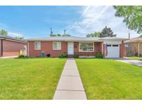 Charming brick home featuring a well-manicured lawn and walkway leading to the front door at 1304 S Harlan St, Lakewood, CO 80232