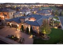 Stunning exterior view of home with dark roof, landscaped yard, and paved driveway leading to a two-car garage at 9617 S Shadow Hill Cir, Lone Tree, CO 80124