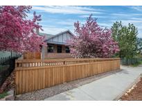 Charming home exterior with a wooden fence and vibrant pink flowering trees creating curb appeal at 3311 N York St, Denver, CO 80205