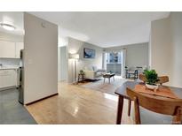 Bright living room featuring hardwood floors, neutral tones, and a sliding door to the outside balcony at 4110 Hale Parkway Pkwy # 3J, Denver, CO 80220