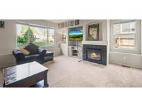 Inviting living room features a cozy fireplace, large windows, and comfortable seating, perfect for relaxation at 11373 Kearney Way, Thornton, CO 80233