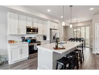 Modern kitchen featuring white cabinetry, stainless steel appliances, and a large island with seating at 6737 S Tempe Ct, Aurora, CO 80016
