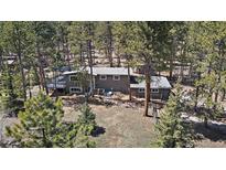 An aerial view of the home reveals mature trees, a deck, and a gray exterior at 29691 Fairway Dr, Evergreen, CO 80439