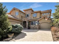 Attractive stucco home featuring stone accents, blue shutters and a three car garage with a basketball hoop at 15295 W Warren Dr, Lakewood, CO 80228
