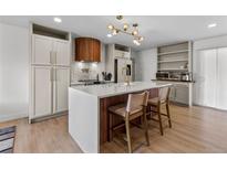 Modern kitchen featuring a large island with seating, custom wood accents, and stainless steel appliances at 690 S Newark Ct, Aurora, CO 80012