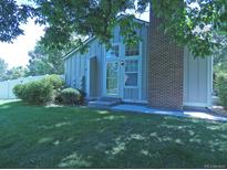 Charming home exterior with brick accent, complemented by a well-maintained lawn and mature trees at 9669 W Chatfield Ave # A, Littleton, CO 80128