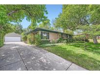 Charming single-story brick home featuring a well-manicured lawn and mature trees at 8600 W 2Nd Ave, Lakewood, CO 80226