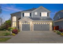 Beautiful two-story home with gray siding, brick accents, three-car garage and manicured landscaping at 15915 E Summit Fox Ave, Parker, CO 80134