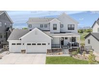 Beautifully designed two-story home featuring a charming front porch, three-car garage, and modern architectural details at 2141 Fountain Cir, Erie, CO 80516
