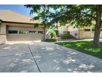 Beige two-car garage with a concrete driveway and beautiful landscaping at 3325 W 111Th Loop # C, Westminster, CO 80031