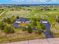Expansive aerial view of a luxurious home with an attached and detached garage on a large, green lot at 34682 Stampede Cir, Elizabeth, CO 80107
