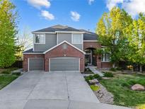 Beautiful two-story home with a well-maintained lawn, mature trees, and a spacious three car driveway at 6155 Puma Pt, Lone Tree, CO 80124