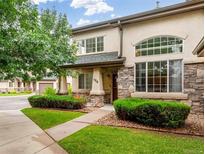 Charming two-story townhome featuring stone accents, manicured landscaping, and a welcoming front entrance at 1415 S Chambers #106 Rd, Aurora, CO 80017
