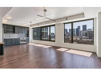 Bright, modern living room with wood floors and city views through large windows at 1750 Wewatta St # 1102, Denver, CO 80202