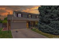 Charming two-story home with a two-car garage, basketball hoop, beautiful lawn, and mature tree at sunset at 7865 S Lafayette Ct, Centennial, CO 80122