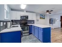 Modern kitchen with stainless steel appliances, blue lower cabinets, white upper cabinets, and attractive countertops at 1585 S Holly St # 109, Denver, CO 80222