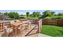 Outdoor deck with dining area, perfect for entertaining, with green yard and treed view at 1791 S Laredo St, Aurora, CO 80017