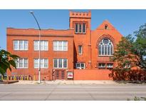 Red brick exterior of a converted loft featuring unique architectural details, large windows, and a welcoming entrance at 225 N Lincoln St # 4, Denver, CO 80203