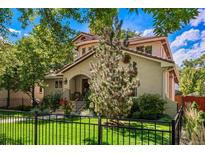 Charming home showcasing a well-manicured lawn, mature trees, and a classic wrought iron fence at 1035 S Elizabeth St, Denver, CO 80209