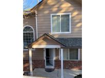 Tan two-story townhome with a covered entryway and brick facade at 6845 S Webster St # E, Littleton, CO 80128