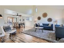 Cozy living room featuring hardwood floors, modern decor, and an open floor plan with an adjacent dining area at 6487 W Weaver Ave, Littleton, CO 80123