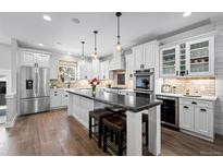 Spacious kitchen features stainless appliances, granite countertops, white cabinetry, and hardwood floors at 2948 S Clarkson St, Englewood, CO 80113