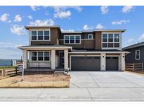 Two story home with large garage, neutral colors, white stone porch accents, and professionally landscaped front yard at 8686 Pennycress Dr, Littleton, CO 80125