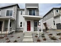 Modern two-story home featuring stone accents, a red front door, and gray siding, offers stylish curb appeal at 22823 E Tufts Ave # B, Aurora, CO 80015