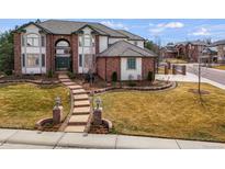 Beautiful brick and white home with a landscaped front yard and inviting walkway with lamp posts at 9188 Buck Hill Dr, Highlands Ranch, CO 80126