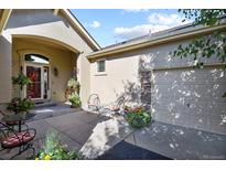 Inviting front entrance with covered porch, seating, and colorful flower arrangements near a two car garage at 42340 Kingsmill Cir, Elizabeth, CO 80107