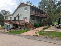 Charming two-story home boasts a spacious deck, landscaped yard, and an inviting entrance at 4724 Hopi Rd, Indian Hills, CO 80454