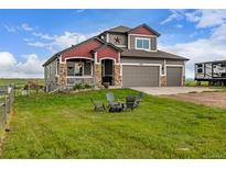 Charming two-story home with a three-car garage, covered porch, and outdoor chairs around a fire pit at 28495 La Donna Vista Ln, Elizabeth, CO 80107