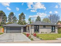 Charming single-story home with a modern exterior, grey brick, beautiful landscaping, a paved driveway, and an attached garage at 3049 S Vine St, Denver, CO 80210