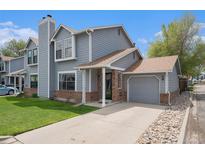 Charming gray two-story home with brick accents, attached garage, and well-manicured lawn at 5250 Cody St, Arvada, CO 80002