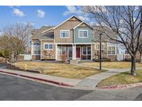 Two-story townhome featuring stone accents, a red front door, and a well-maintained front lawn at 13271 Holly St # D, Thornton, CO 80241
