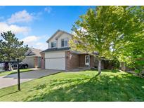 Charming two-story home with a brick facade and a well-manicured lawn on a beautiful day at 2430 S Halifax Way, Aurora, CO 80013